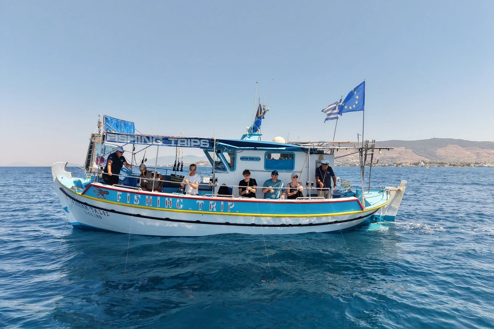 De boot van opzij met het Fishing Trip-zonnedak en gasten aan de reling